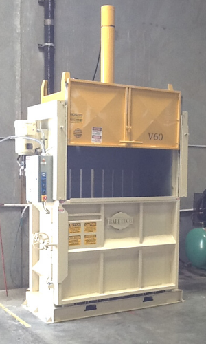 a yellow and white vertical baler with the "Baletech" logo pictured in a factory