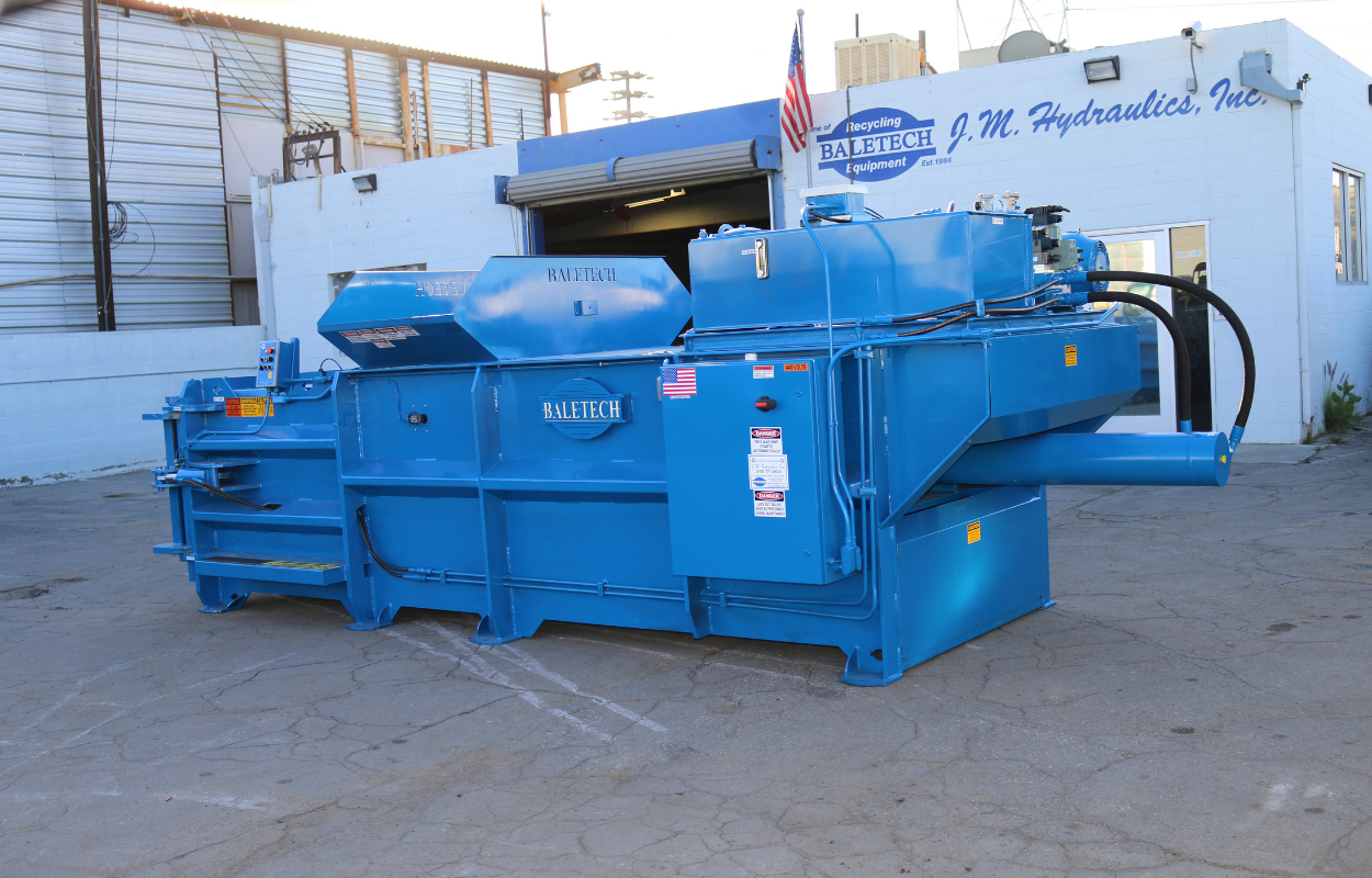 a brand new bright blue Baletech baler pictured outside of the Baletech J.M. Hydraulics building in Sun Valley, California