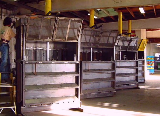 a worker repairing the first in a row of steel gray vertical balers pictured inside a factory