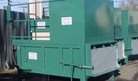 a row of three green Stationary Compactors installed outside of a building