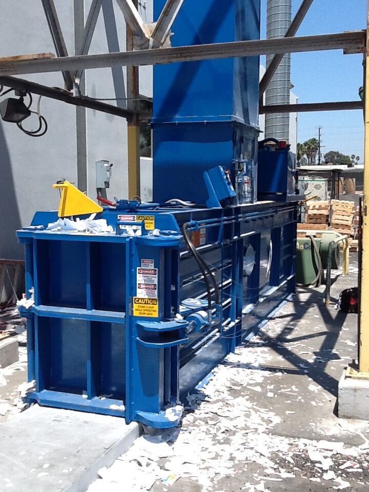 large blue custom baler system set up outside an industrial building