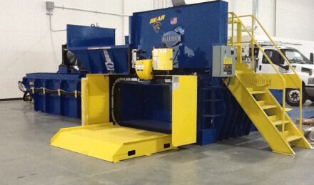 a blue horizontal recycling baler pictured with yellow stairs leading up to the top of the baler