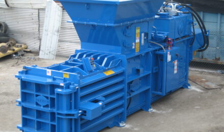 a shiny new horizontal blue baler bolted to the concrete outside