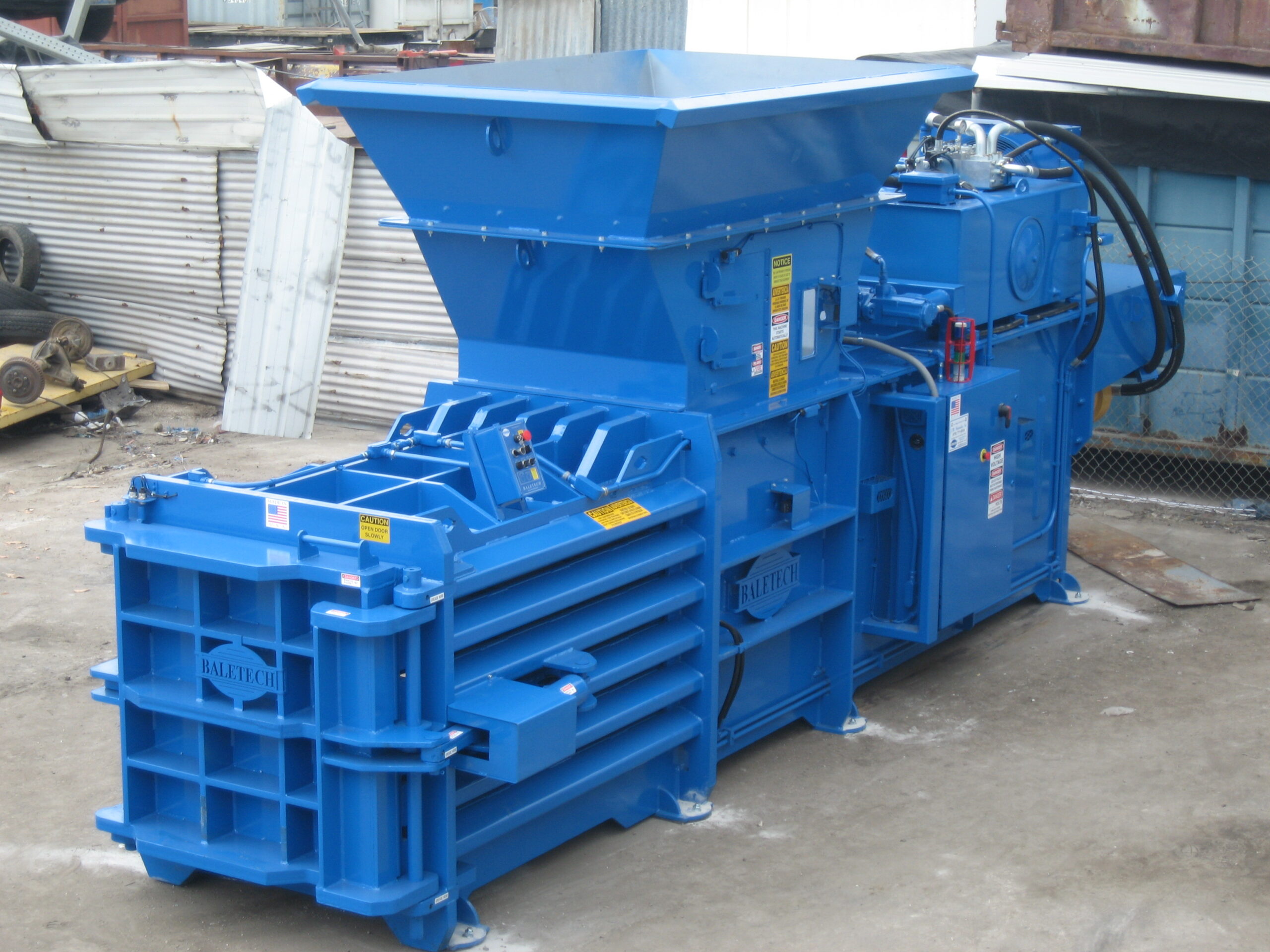 a shiny new horizontal blue baler bolted to the concrete outside